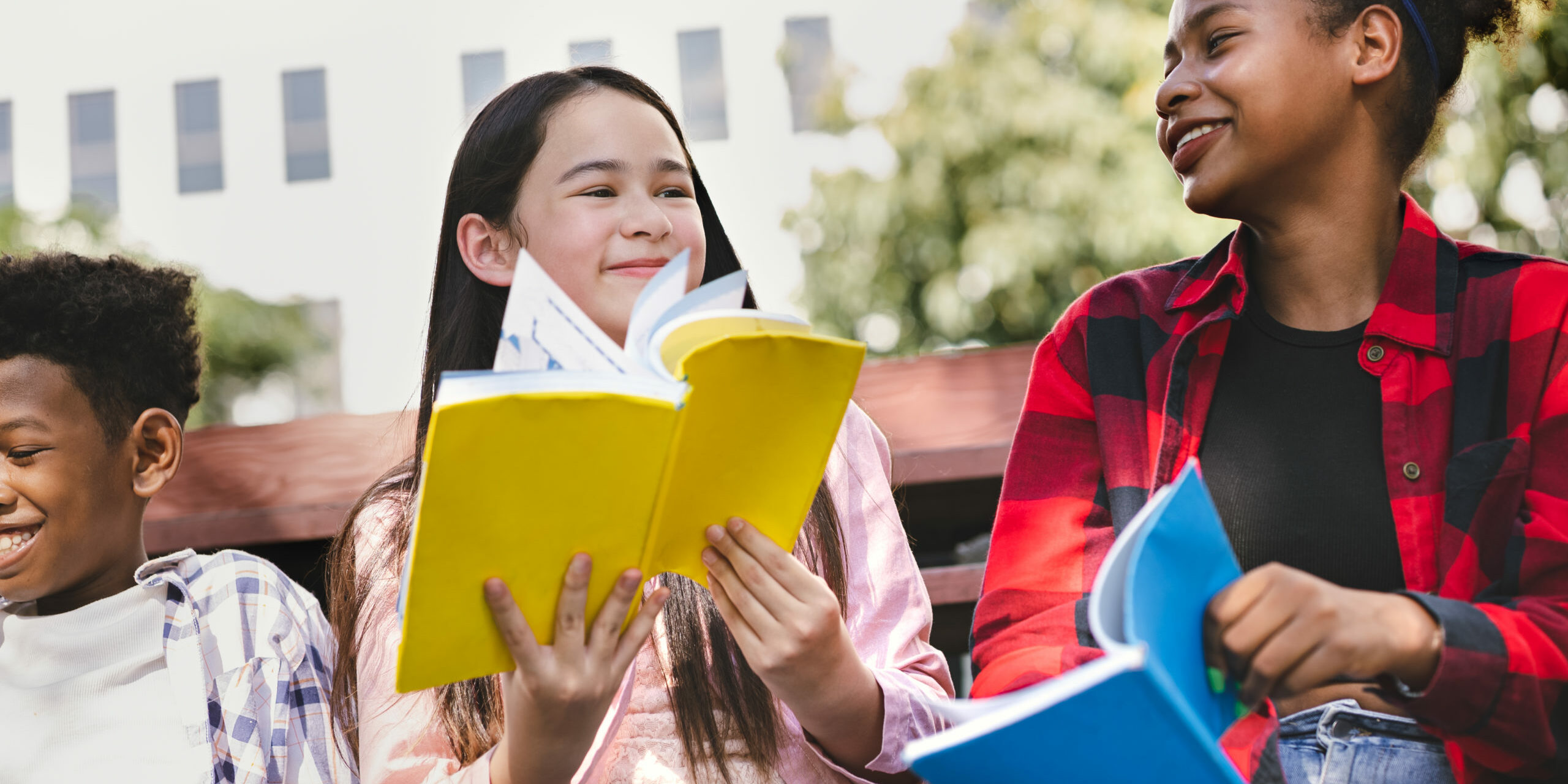 student-girl-reading-book-with-friend-at-school-park