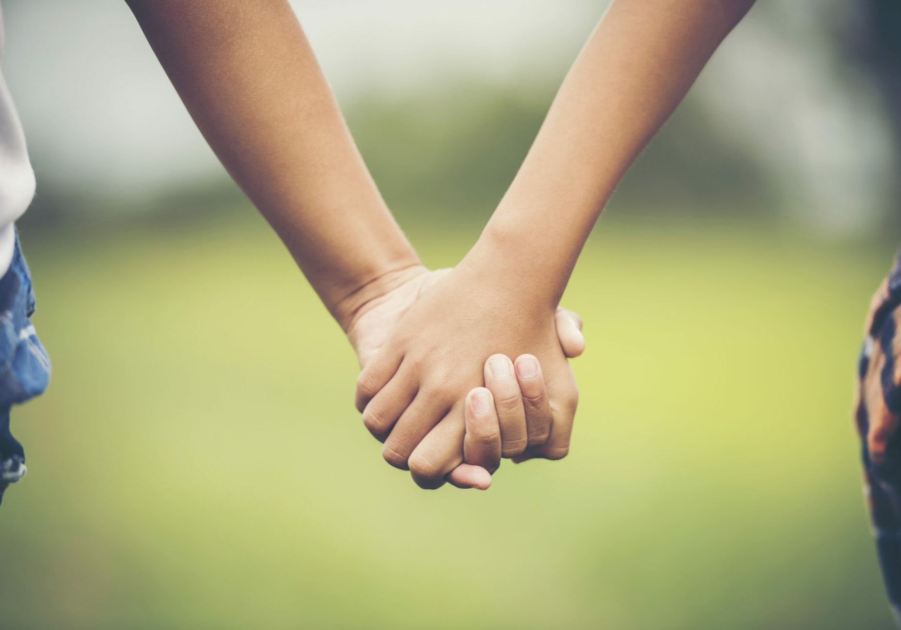 Two little girl friendship hand holding together in the park