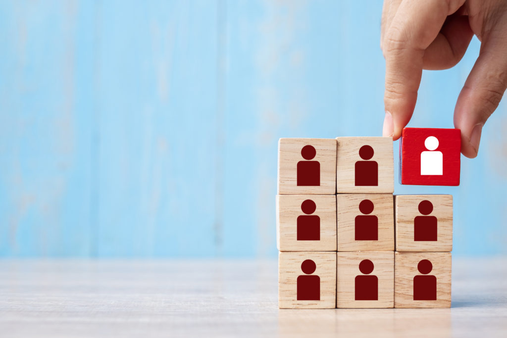 Business man hand placing or pulling Red wooden block with white person icon on the building. People, Business, Human resource management, Recruitment, Teamwork, strategy and leadership Concepts